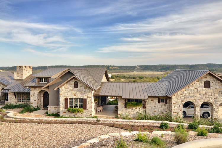 Bronze standing-seam metal roof over a Hill Country stone ranch home