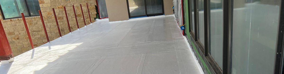 Grey PMMA waterproofing membrane freshly applied to a covered terrace