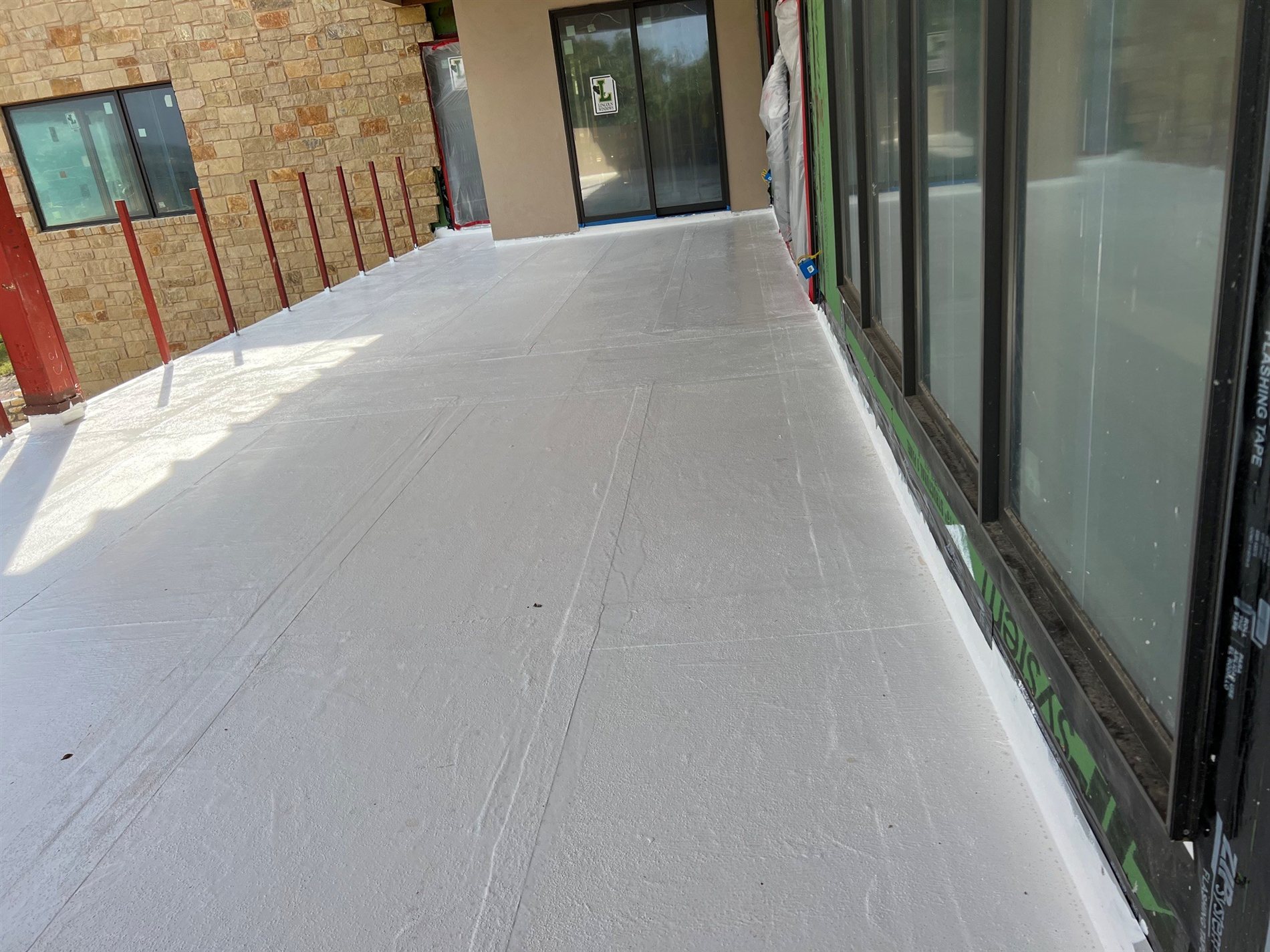 Grey PMMA waterproofing membrane freshly applied to a covered terrace before the finished floor goes down