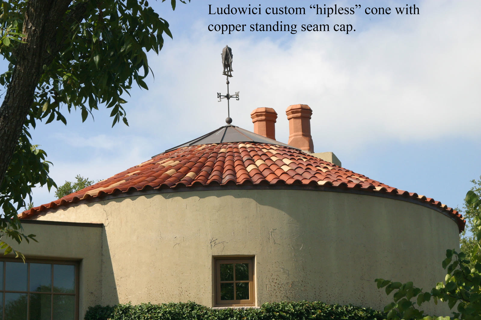 Custom hipless clay tile cone roof with a copper standing-seam cap and weathervane