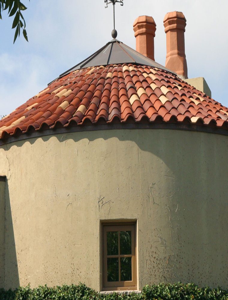 Custom clay barrel-tile cone roof with terracotta chimney pots