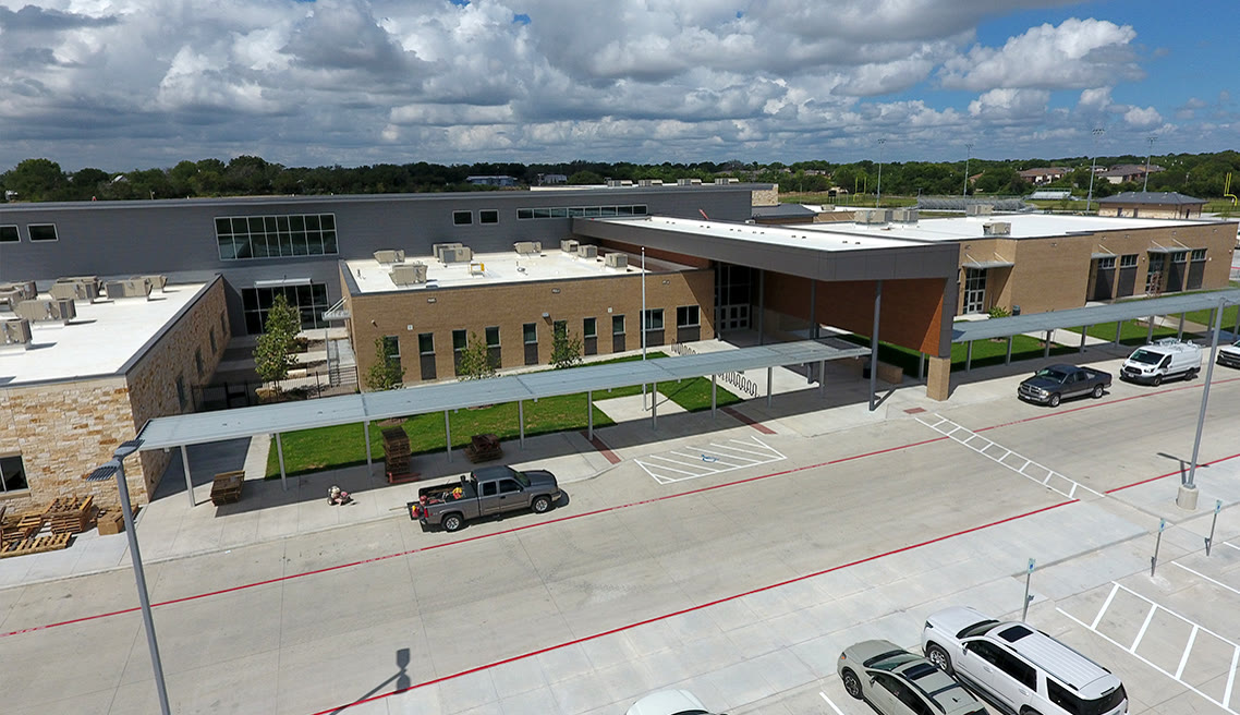 Exterior of a new middle school with a low-slope membrane roof and metal wall panel accents