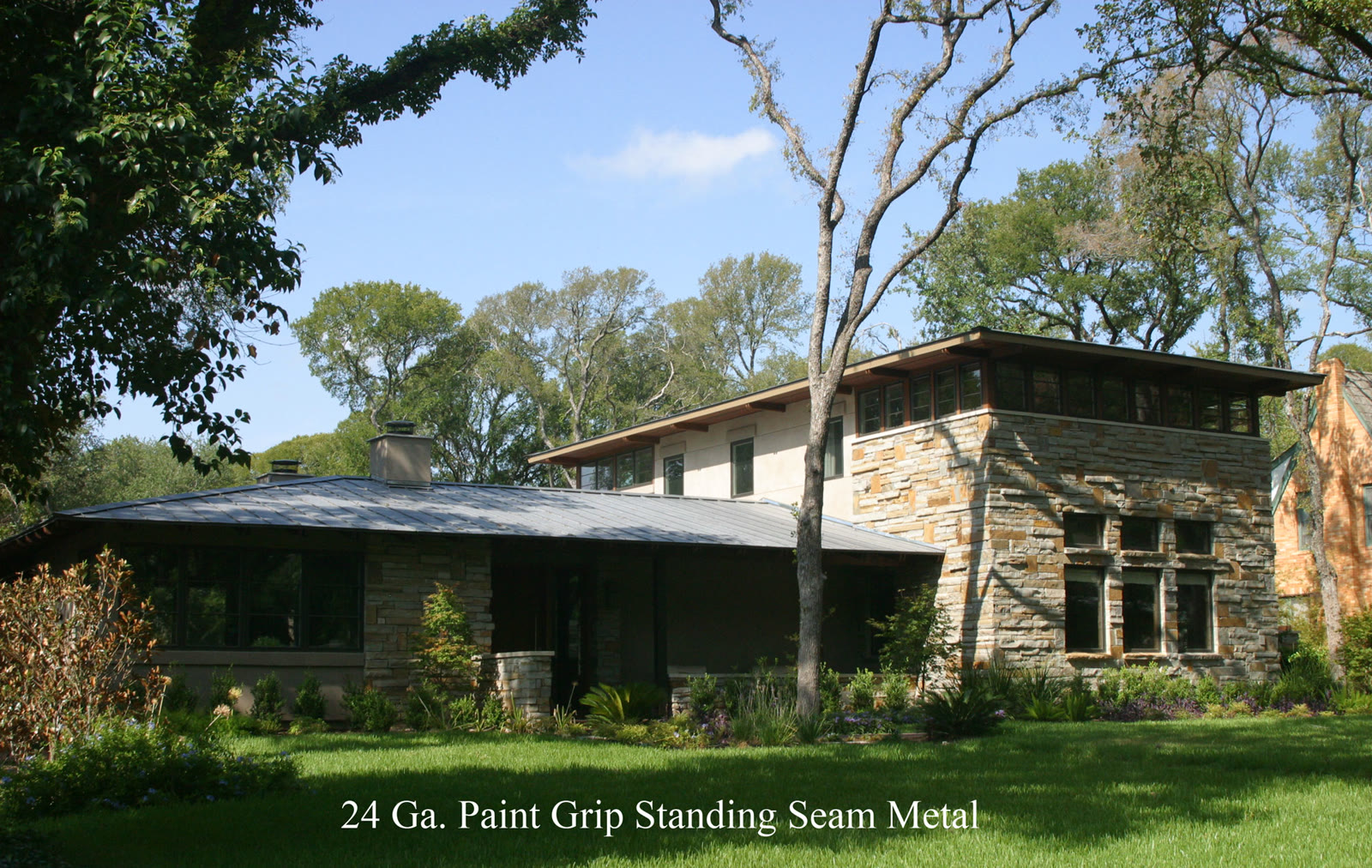 Low-pitched standing-seam metal roof over a Prairie-style stone home
