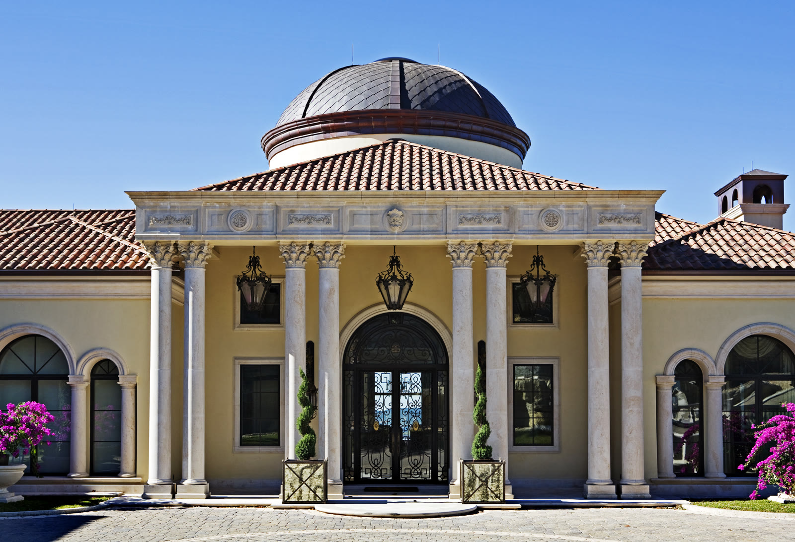 Grand entry portico with a clay tile roof and a copper dome